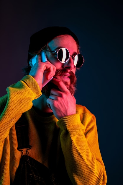 Free photo talking on phone in sunglasses. caucasian man's portrait on gradient  space in neon light