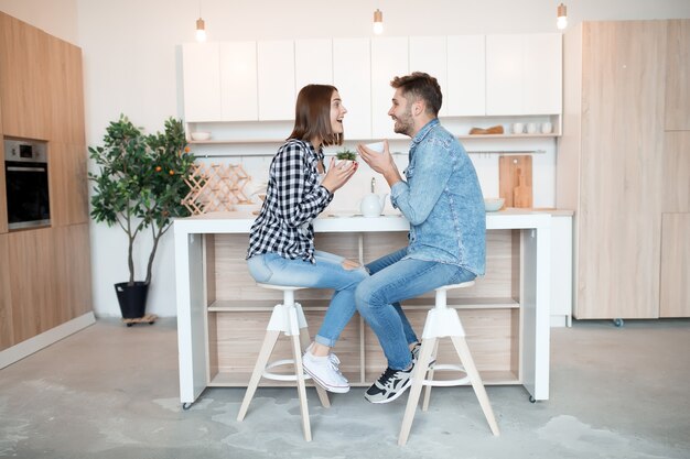 キッチン、朝食、朝のカップルで一緒に若い幸せな男と女の話、笑顔、お茶