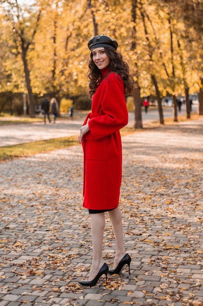따뜻한 빨간 코트 가을 유행 패션, 거리 스타일, 베레모 모자를 입고 공원에서 산책하는 곱슬 머리를 가진 키 크고 매력적인 세련된 웃는 마른 여자