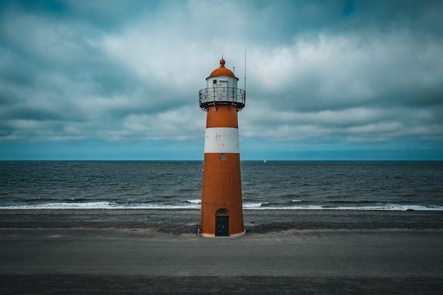 Tall lighthouse at the North sea under a cloudy sky