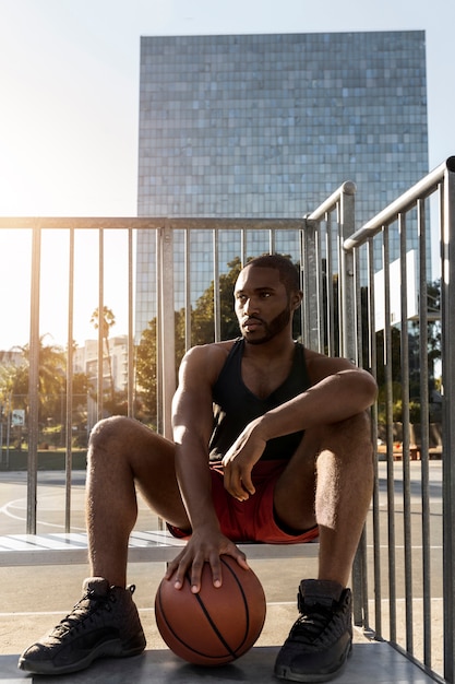 Foto gratuita uomo alto che si prende una pausa dal basket