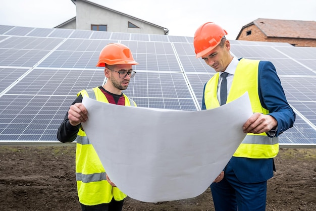 Tall men in work clothes are considering whether to install solar panels in the open air. the concept of caring for solar panels under the sky