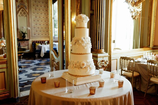 Tall white tired wedding cake stands on the round table