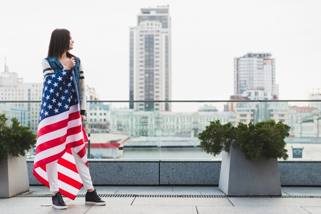 Tall woman on balcony wrapped in American flag