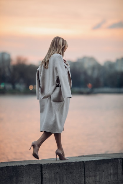 Free photo tall woman in shoes and coat walking near the river