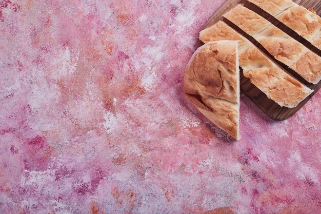 Ломтики хлеба тандыра на розовом столе.