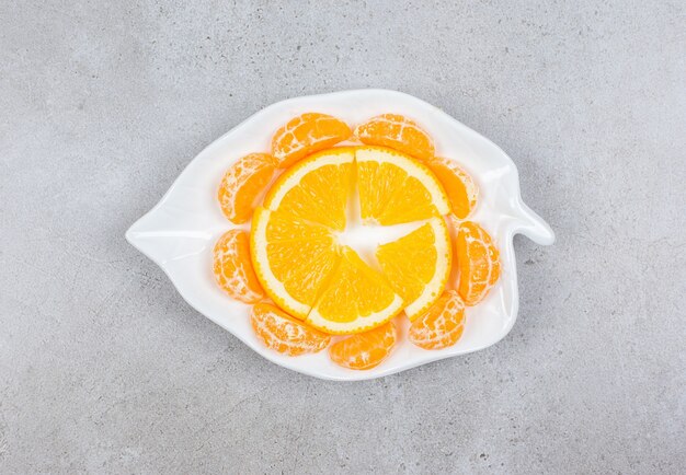 Tangerine and orange slices on white plate.