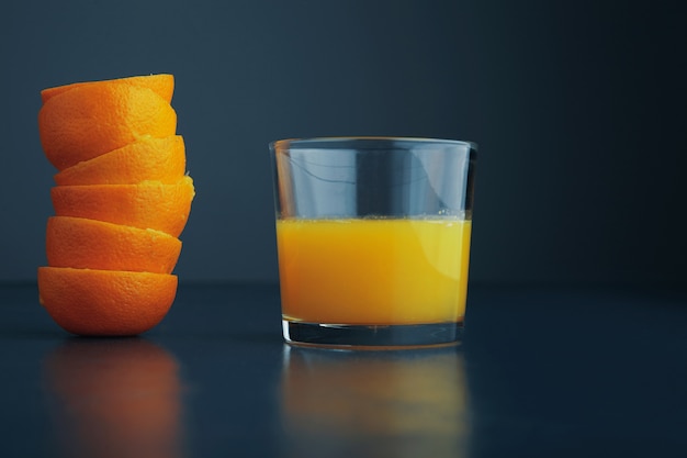 素朴な青いテーブルの側面図で分離された朝食用の新鮮な健康的な柑橘系オレンジジュースとガラスの近くのみかんの皮のコート
