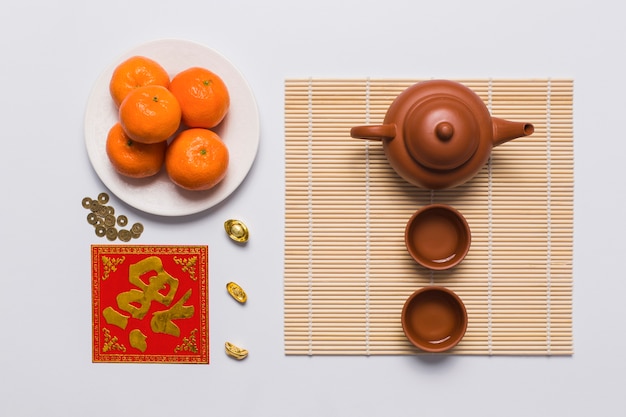 Tangerines near tea set on bamboo napkin