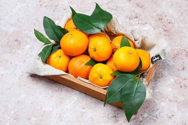 Tangerines (oranges, clementines, citrus fruits) with green leaves on concrete surface with copy space