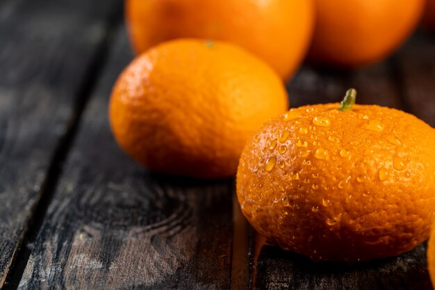 Tangerines with drops of water on a wooden table