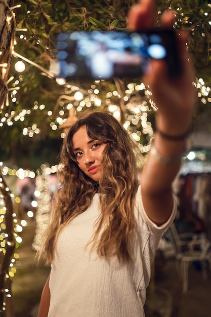 Foto gratuita donna caucasica abbronzata che prende un selfie in un parco di divertimenti