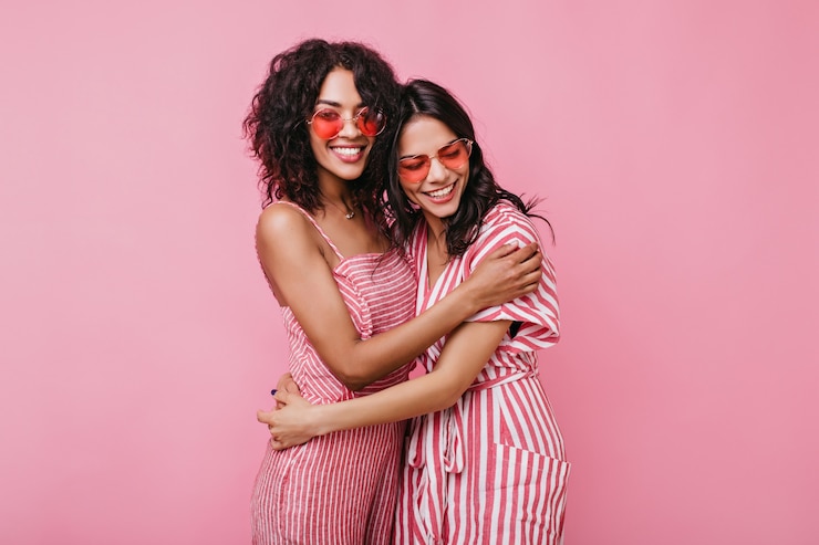 Free Photo tanned girls with sincere white smiles rejoice photo shoots. girlfriends in summer jumpsuits posing .