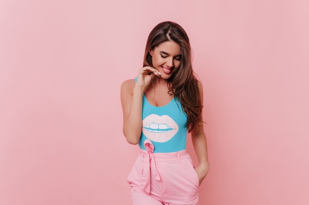 Tanned spectacular girl in funny tank-top posing on pink space