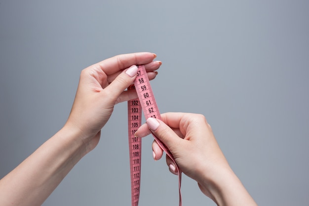 Tape in female hands on gray space