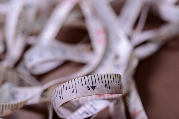 Premium Photo | Measuring tape rolled out randomly on red background.