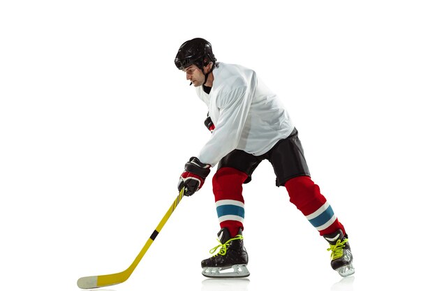 Target. Young male hockey player with the stick on ice court and white wall. Sportsman wearing equipment and helmet practicing. Concept of sport, healthy lifestyle, motion, movement, action.