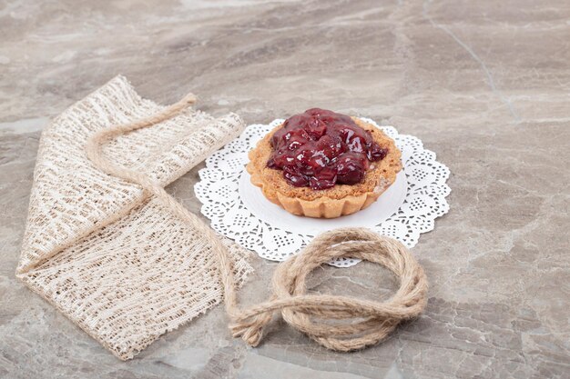 Tart cake with rope and burlap on marble surface. 