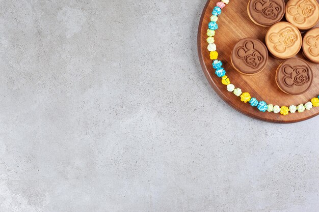 대리석 배경에 나무 쟁반에 팝콘 사탕으로 둘러싸여 타트 쿠키. 고품질 사진