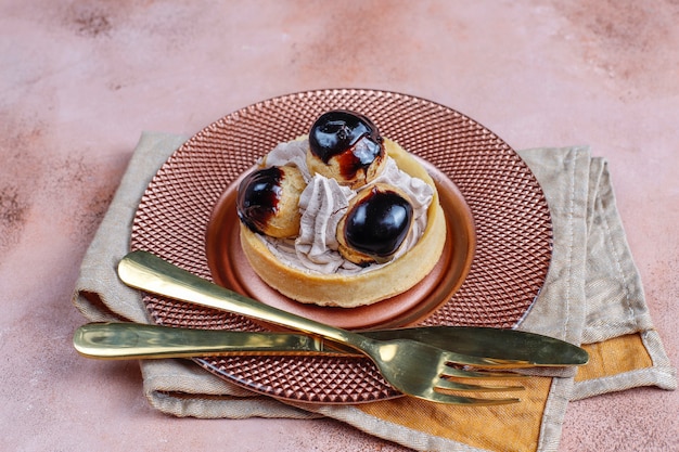 Crostata con profiteroles sopra con panna montata.