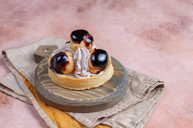 Tart with profiteroles on top with whipped cream.