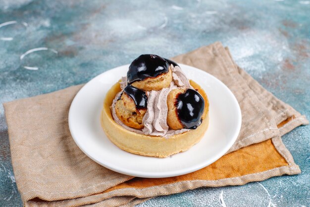 Tart with profiteroles on top with whipped cream.