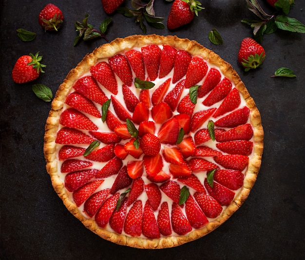 Tart with strawberries and whipped cream decorated with mint leaves. Top view