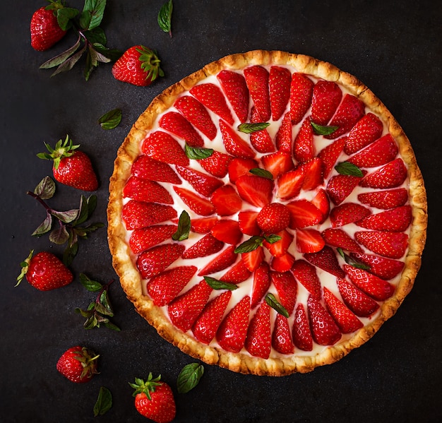 Tart with strawberries and whipped cream decorated with mint leaves. Top view