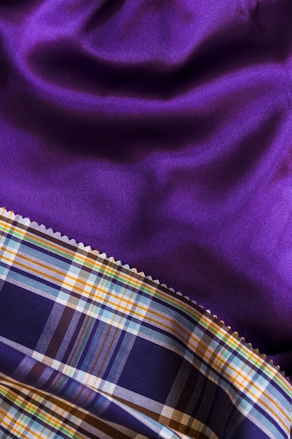Free photo tartan pattern textile on smooth purple fabric