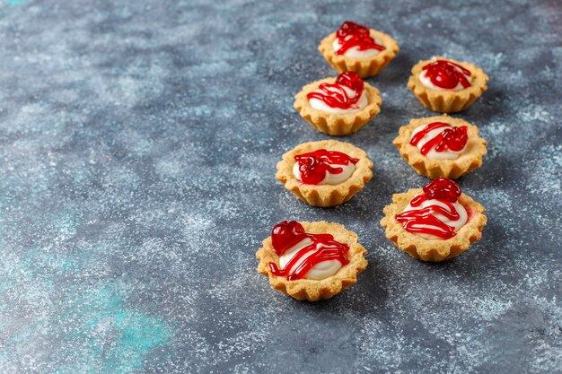 Tartlets with white chocolate filling and berry jam on top.