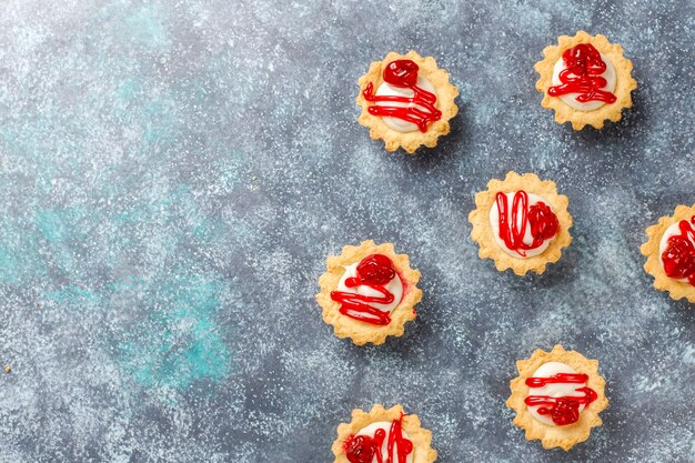 Tartlets with white chocolate filling and berry jam on top.