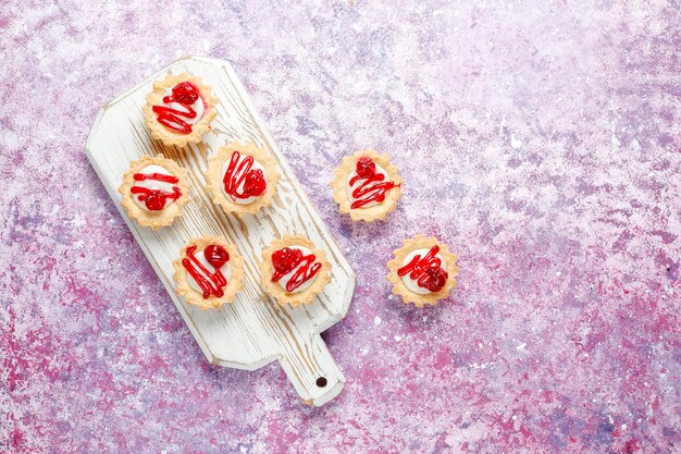 Tartlets with white chocolate filling and berry jam on top.