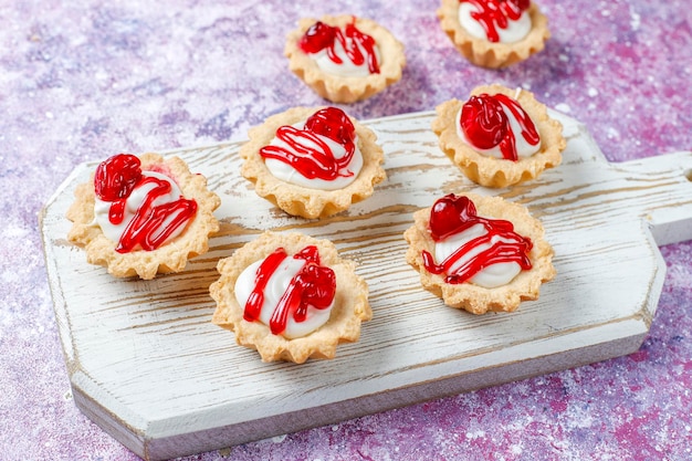 Tartlets with white chocolate filling and berry jam on top.