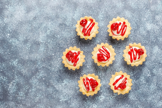 Tartlets with white chocolate filling and berry jam on top.