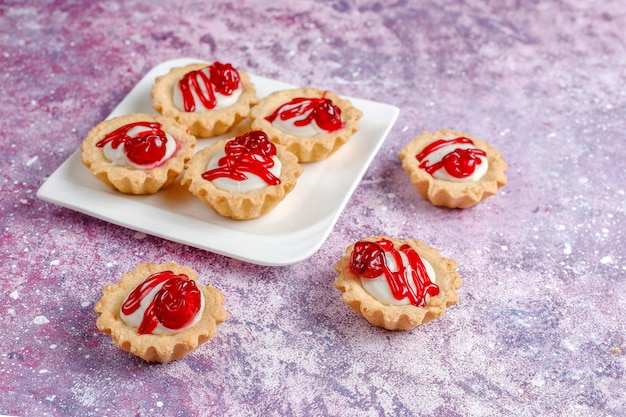 Tartlets with white chocolate filling and berry jam on top.