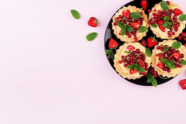 민트 잎으로 장식 된 딸기, 건포도 및 휘핑 크림 타르트