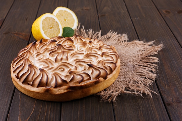 Tasteful lemon pie with white cream served on wooden table