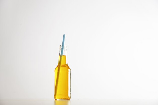 Tastu sparkling drink with blue drinking straw inside opened rustic glass bottle isolated on white