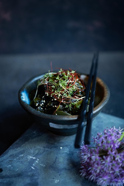 Вкусный салат из водорослей со специями и кунжутом подается в миске на темном фоне
