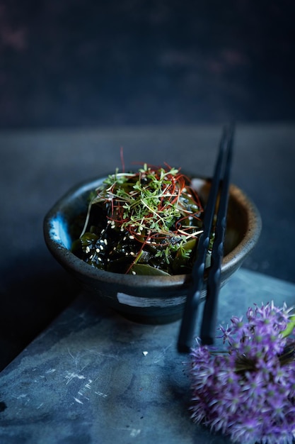 Tasty algae salad with spices and sesam served in bowl on dark background