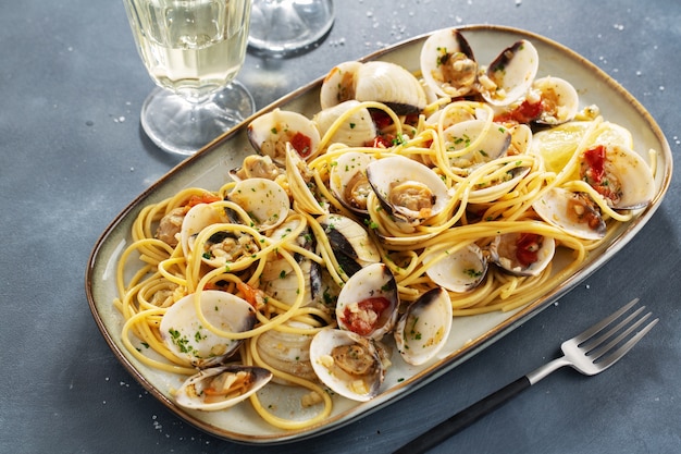 Вкусные аппетитные свежие домашние макароны из морепродуктов из моллюсков с чесноком и белым вином на тарелке. Крупный план.
