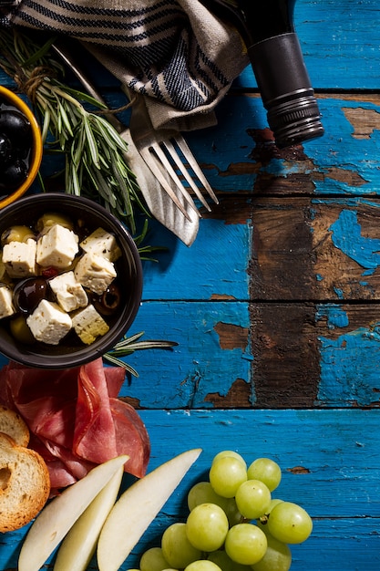 おいしい食欲をそそるイタリアン地中海ギリシャ料理食材ワインブドウ肉オリーブブルーの古いテーブルのチーズ