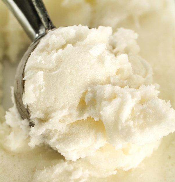 Tasty appetizing pure vanilla creamy ice cream with in ice cream spoon. Closeup.