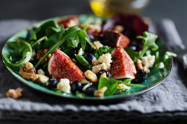 Free photo tasty appetizing salad with arugula figs cheese and nuts served on table. closeup