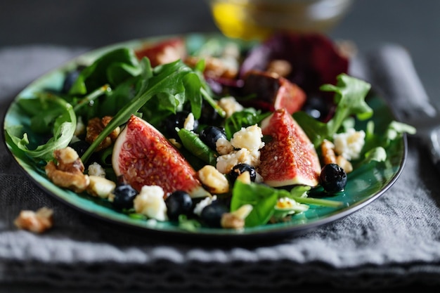 Tasty appetizing salad with arugula figs cheese and nuts served on table. Closeup