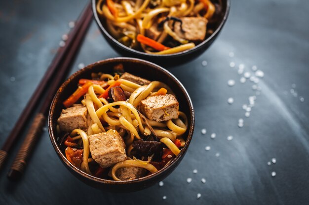 Tasty asian noodles with cheese tofu and vegetables in bowls