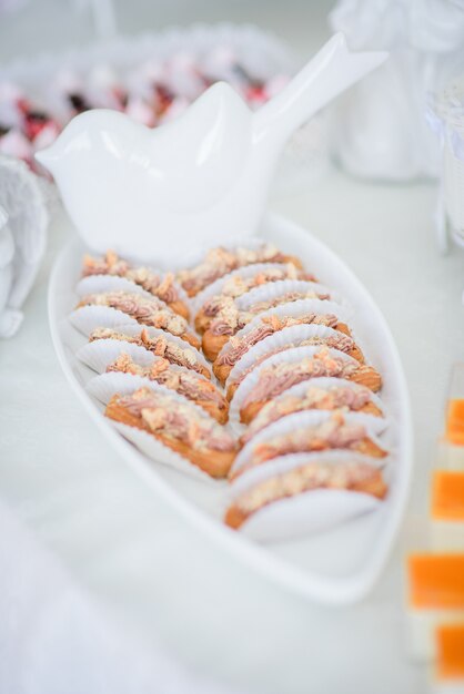 Tasty baked sweets stand on long white dish 