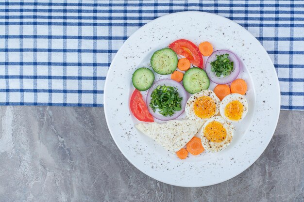 Tasty boiled eggs with spices and vegetables on tablecloth. High quality photo
