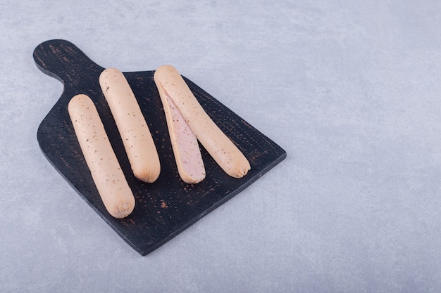 Tasty boiled sausages on black board.