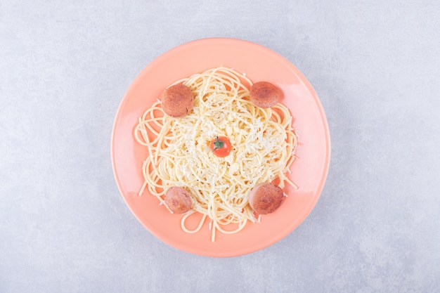 Foto gratuita spaghetti bolliti saporiti con le salsiccie sul piatto arancio.